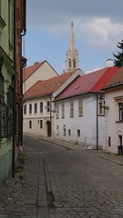 Obraz premium Cobblestone Street with Historic Church Spire in Bratislava Old Town