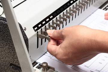 Using the left hand adorned gear to penetrate the paper. Preparation for Binding