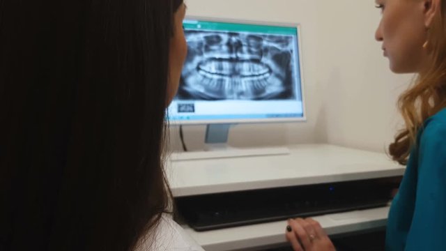 Dentist showing to patient teeth x-ray image on computer, dental diagnosis