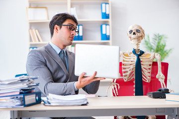 Businessman working with skeleton in office