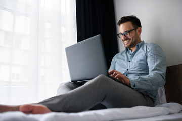 Businessman using laptop computer, working at his hotel room. Traveling for work. 