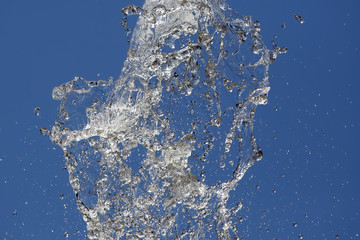 Splashes of flying water from the fountain against the blue sky