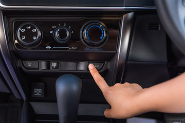 Close up of woman hand pressing turn on air-conditioner button a car