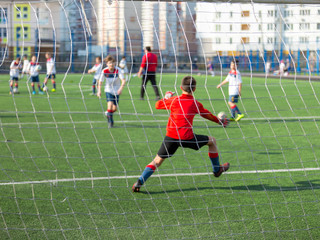 Active happy boy in motion, having fun outdoor, playing football in sportive summer camp, catching ball, best goalkeeper in football team