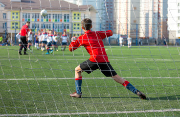 Active happy boy in motion, having fun outdoor, playing football in sportive summer camp, catching ball, best goalkeeper in football team