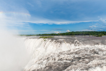 Wide angle landscape view of Iguazu waterfalls on a sunny day in summer. Photo taken from the Argentinian side at the Devil’s throat.