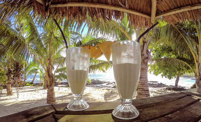 Half full glasses of tropical pina colada cocktail drink with pineapple garnish in glass with...