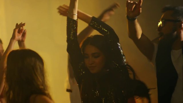 Medium shot of ecstatic crowd jumping and dancing to rhythmic music at nightclub party