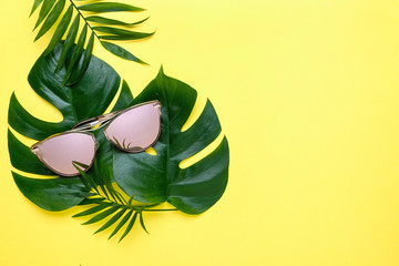 Fototapeta na wymiar Summer composition of tropical palm leaves, Monstera. yellow background with pink glasses. Concept - Summer vacation
