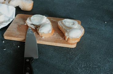 Closeup sandwiches with bread, butter and eggs on wooden board in black background. Making a sandwiches.