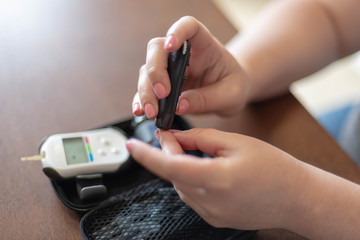 Woman uses lancet to prick finger for home blood glucose test