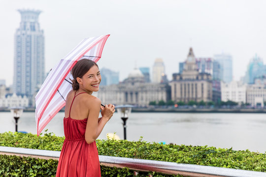 Chinese umbrella woman in rain. Urban landscape panorama of Shanghai city Bund, Pudong Huangpu district, rainy summer day. Tourist traveling in Shanghai, China, Asia travel.