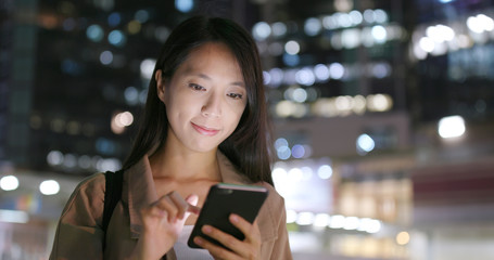 Woman sending message on cellphone in city at night