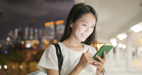 Woman looking on cellphone in city at night