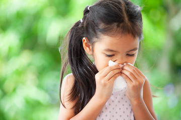 Sick asian little child girl wiping and cleaning nose with tissue on her hand