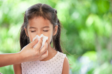 Mother hand holding tissue and help sick daughter wiping and cleaning nose