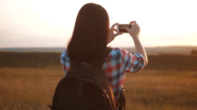 Hipster hiker silhouette girl is shooting video of beautiful nature sundown on cell telephone smartphone slow motion video. Female tourist is taking photo with mobile phone camera. girl tourist