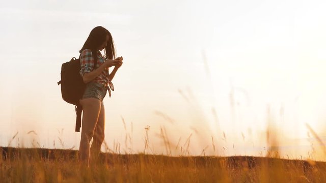Hipster hiker silhouette girl is shooting video of beautiful nature sundown on cell telephone smartphone slow motion video. Female tourist is taking photo with mobile phone camera. lifestyle female