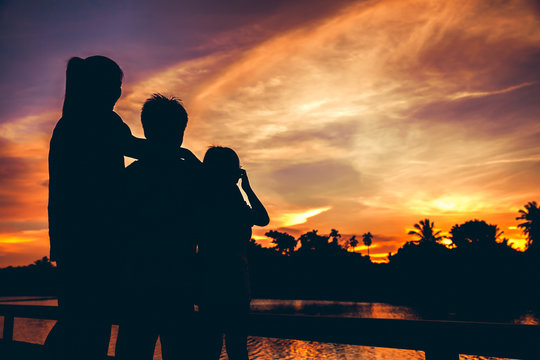 Silhouette of mother with son and daughter enjoying view at riverside.