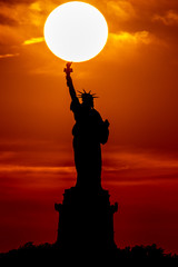 Sun behind statue of liberty