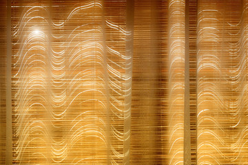 The sun's rays make their way through the closed bamboo blinds to the curtain.