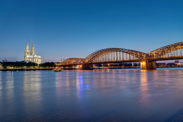 Naklejka na ściany i meble The river Rhine, the Cologne Cathedral and the Hohenzolllern bridge in Cologne at dusk