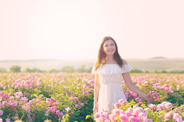 Fototapeta na wymiar Beautiful young woman posing near roses in a garden.