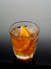 Closeup glass of negroni cocktail decorated with citrus on dark background.
