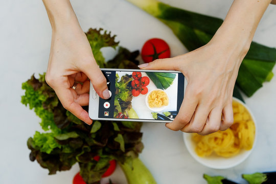 Food blogger concept. Hands with the phone close-up pictures of food.