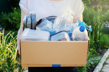 Woman holding a carton with plastic bottles, prepairing for recycling