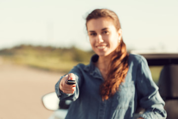 Young pretty woman standing near convertible with keys in hand