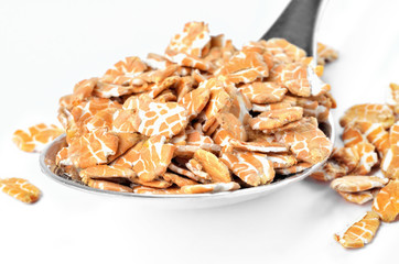 Close-up of pile of oat flakes on a spoon isolated on a white background