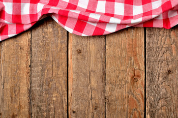 Red checkered tablecloth top frame on vintage wooden table background - view from above