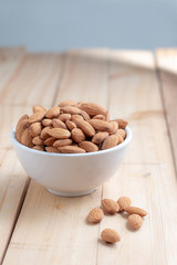 Almond nut in a ceramic bowl against wooden table