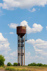 Old rusty water tower in the green field