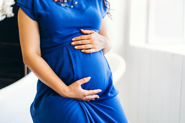 Cute pregnant woman near white wooden wall