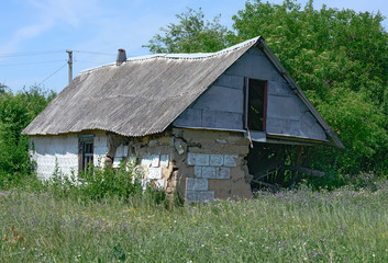 Fototapeta na wymiar Abandoned small rural hut with completely ruined corner in Ukraine.