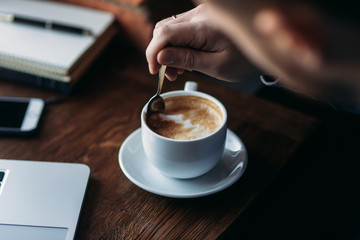 Cappuccino. Man with a beard uses a laptop in a cafe