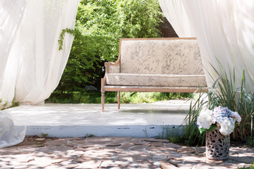 Luxury modern gazebo with soft furniture and curtains inside garden. Summer wedding ceremony...