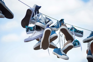 Pairs of sneakers hanging on cable
