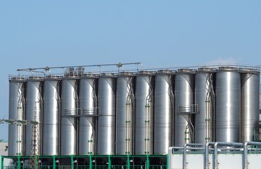 Long row of stainless storage silos for liquids and differents types of free flowing raw materials 