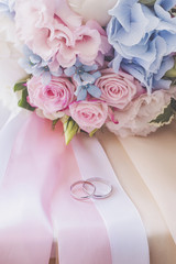 Wedding rings on ribbons with bridal bouquet
