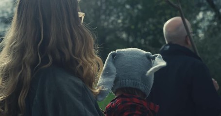 Mother carrying toddler walking with grandfather in forest