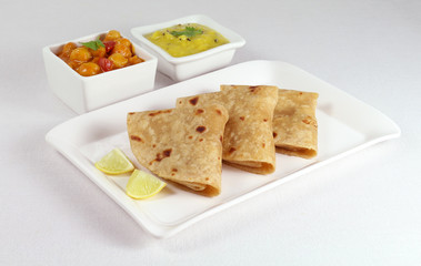 Chapati or Indian flat bread, is a healthy, and vegetarian food, eaten for breakfast, lunch or dinner, with dal and chana dal masala as side dishes, on a plate.