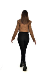 full length portrait of brunette girl wearing brown leather jacket.   standing pose with back to...