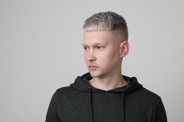 Young man with gray hair in casual clothes on white and gray background. Portrait in the studio. Creative hair coloring.