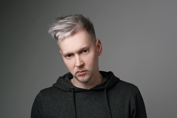 Young man with gray hair in casual clothes on white and gray background. Portrait in the studio. Creative hair coloring.