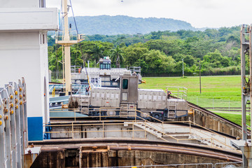 Fototapeta premium Electric locomotives, known as mules, guiding a container ship through Gatun Locks, part of Panama Canal.