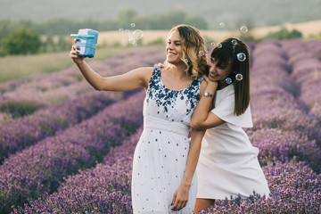Two woman having fun with soap bubbles at flower field