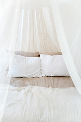 Four-poster bed with two pillows. Scandinavian simplicity design. Eco loft apartments.